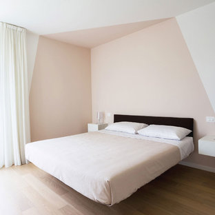 Immagine di una camera matrimoniale minimal con parquet chiaro, pareti multicolore e pavimento beige