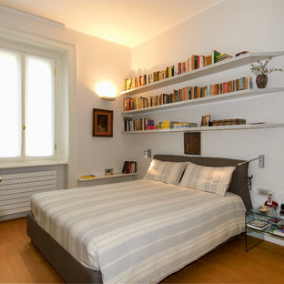 Immagine di una camera da letto design con pareti bianche, pavimento in legno massello medio e pavimento marrone