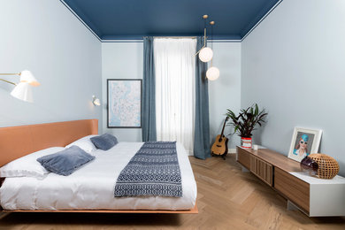 Imagen de dormitorio principal moderno con paredes azules y suelo de madera clara