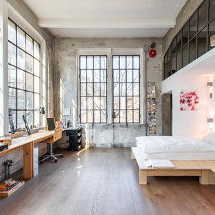 Ispirazione per una grande camera matrimoniale industriale con parquet scuro, pavimento marrone e pareti grigie