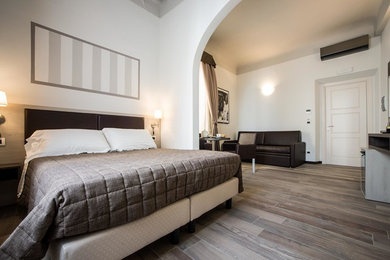 Diseño de habitación de invitados minimalista con paredes blancas, suelo de baldosas de porcelana y suelo marrón