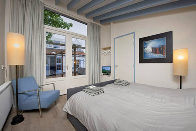 Foto di una camera degli ospiti stile marino di medie dimensioni con pareti bianche, parquet chiaro e pavimento beige