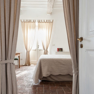 Modelo de dormitorio principal, campestre, con paredes blancas, suelo de ladrillo y suelo rojo