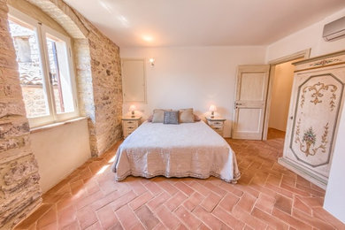 Immagine di una camera matrimoniale mediterranea di medie dimensioni con pareti bianche e pavimento in terracotta