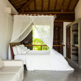 Foto di una camera da letto tropicale con pareti bianche, pavimento in cemento e pavimento grigio