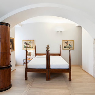 Ejemplo de dormitorio principal, mediterráneo, con paredes blancas, suelo de madera clara, estufa de leña y marco de chimenea de metal