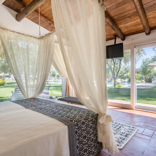 Esempio di una camera da letto tropicale con pavimento in terracotta e pavimento rosso