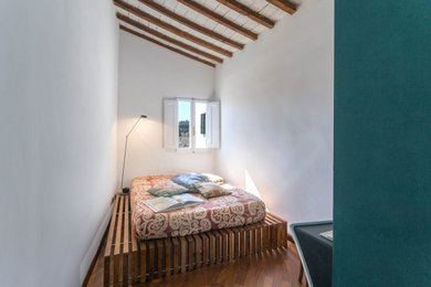 Imagen de dormitorio principal actual pequeño con paredes blancas, suelo de madera oscura, chimeneas suspendidas, marco de chimenea de yeso y vigas vistas