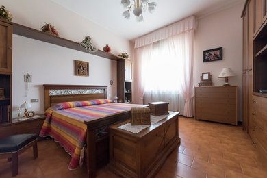 Ejemplo de dormitorio principal campestre grande con paredes blancas y suelo de baldosas de terracota