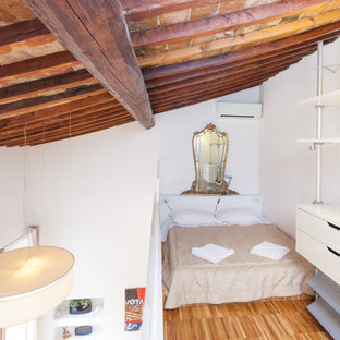 Idee per una camera da letto stile loft design con pareti bianche, pavimento in legno massello medio, pavimento marrone, travi a vista e soffitto a volta