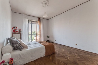 Foto di una camera matrimoniale minimalista con pareti bianche, pavimento in legno verniciato e nessun camino
