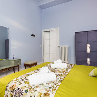 Modelo de dormitorio ecléctico, pequeño, con paredes púrpuras, suelo de madera en tonos medios y suelo marrón