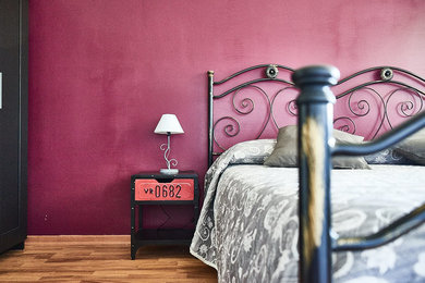 Immagine di una grande camera matrimoniale design con pareti rosse e parquet chiaro