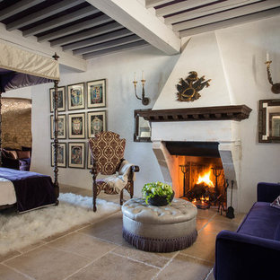Diseño de dormitorio principal, clásico, grande, con paredes blancas, suelo de piedra caliza, chimenea tradicional y marco de chimenea de piedra