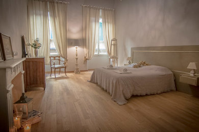 フィレンツェにある広いトラディショナルスタイルのおしゃれな主寝室 (グレーの壁、淡色無垢フローリング、暖炉なし、茶色い床) のインテリア