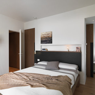 Foto di una camera da letto design con pareti bianche, parquet chiaro e pavimento marrone