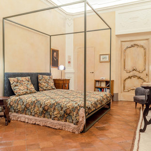 Ispirazione per una camera da letto mediterranea con pareti beige, pavimento in terracotta e pavimento marrone