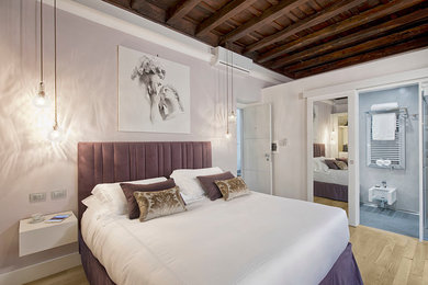 Exempel på ett eklektiskt sovrum, med lila väggar och ljust trägolv