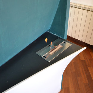 Immagine di una piccola camera matrimoniale design con pareti bianche, parquet scuro, camino sospeso, cornice del camino in intonaco e travi a vista