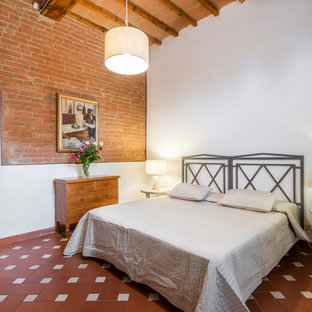Esempio di una camera da letto country con pareti rosse, pavimento in terracotta e pavimento rosso
