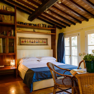Esempio di una camera da letto mediterranea con pareti gialle, pavimento in legno massello medio e pavimento marrone