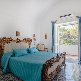 Immagine di una camera da letto mediterranea con pareti bianche, pavimento grigio e soffitto a volta