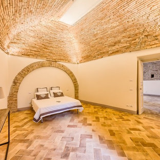 This is an example of a mid-sized mediterranean guest bedroom in Other with beige walls and terra-cotta floors.