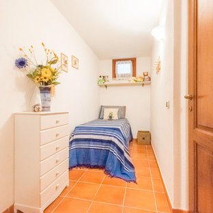 Inspiration for a beach style guest bedroom in Other with white walls and terra-cotta floors.