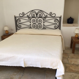 Imagen de dormitorio principal, rústico, de tamaño medio, con paredes blancas y suelo de piedra caliza