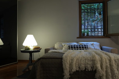 Foto di una piccola camera da letto stile loft design con pareti grigie, pavimento in legno massello medio e pavimento marrone