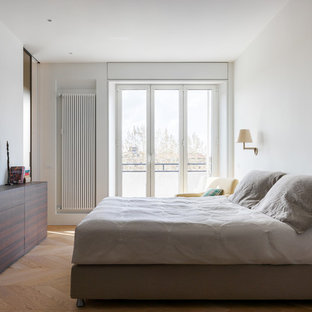 Foto di una camera matrimoniale moderna con pareti bianche, parquet chiaro e pavimento beige