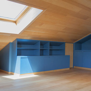Imagen de dormitorio tipo loft, minimalista, de tamaño medio, con suelo de madera pintada, chimenea tradicional y marco de chimenea de madera
