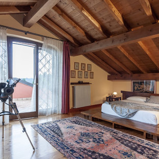 Esempio di una camera da letto stile loft mediterranea con pareti beige, pavimento in legno massello medio e pavimento marrone
