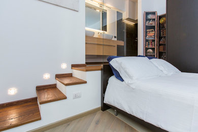 Kleines Modernes Hauptschlafzimmer mit weißer Wandfarbe und braunem Holzboden in Mailand