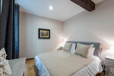 Esempio di una piccola camera matrimoniale country con pareti beige, pavimento in legno massello medio e pavimento marrone