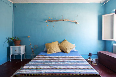 Cette photo montre une chambre parentale méditerranéenne avec un mur bleu, tomettes au sol et un sol rouge.