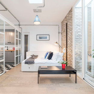 Immagine di una camera da letto industriale con pareti bianche, parquet chiaro e pavimento beige