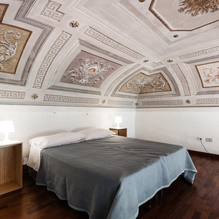 Immagine di una camera da letto mediterranea con pareti bianche, parquet scuro e pavimento marrone