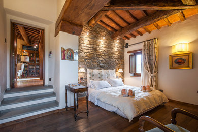 Esempio di una camera degli ospiti mediterranea con pareti bianche, parquet scuro e pavimento marrone