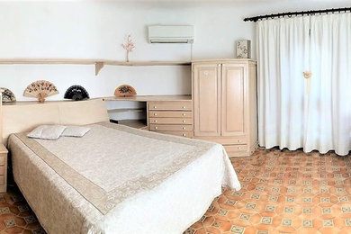 Modelo de dormitorio principal mediterráneo grande con paredes blancas, suelo de baldosas de cerámica y suelo beige