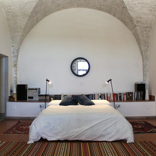 Ejemplo de dormitorio tipo loft, contemporáneo, de tamaño medio, con paredes blancas, suelo de baldosas de terracota y suelo rojo