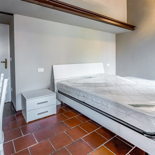 Imagen de habitación de invitados actual, pequeña, con paredes grises, suelo de baldosas de cerámica y suelo rojo