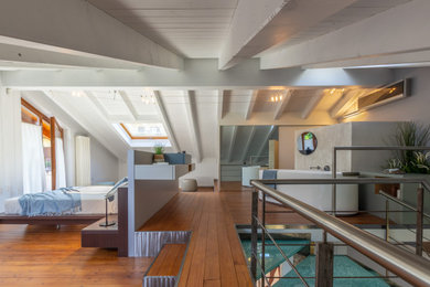 Esempio di un'ampia camera da letto stile loft contemporanea con pareti blu, pavimento in legno verniciato e pavimento marrone