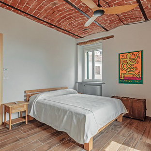 Immagine di una camera da letto mediterranea con pareti bianche e pavimento marrone