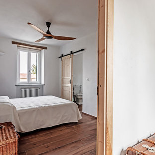 Ispirazione per una camera da letto mediterranea con pareti bianche e pavimento marrone