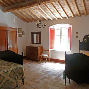Ejemplo de dormitorio principal, de estilo de casa de campo, de tamaño medio, con paredes blancas, suelo de ladrillo y suelo rojo
