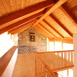 Ejemplo de dormitorio tipo loft, rural, de tamaño medio, con paredes blancas, suelo de madera clara y suelo naranja
