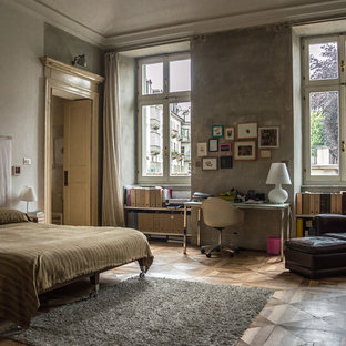 Foto di una camera da letto industriale con pareti grigie, pavimento in legno massello medio e pavimento marrone