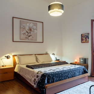 Esempio di una camera da letto design con pareti bianche, pavimento in legno massello medio e pavimento marrone