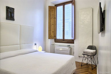 Esempio di una camera matrimoniale minimalista di medie dimensioni con pareti bianche e pavimento in legno massello medio